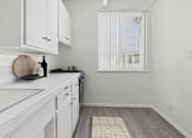 Thumbnail 2 of 16 - A kitchen with white cabinets and a wooden cutting board on the counter.