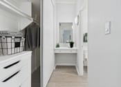 Thumbnail 7 of 16 - A white kitchen with a small table and a mirror.