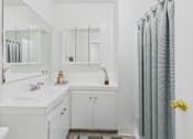 Thumbnail 9 of 16 - A white bathroom with a sink, mirror, and shower.