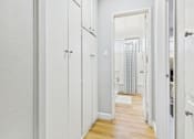 Thumbnail 18 of 37 - A white hallway with a doorway leading to a bathroom.