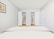 Thumbnail 17 of 37 - A bedroom with a large bed and a wardrobe with clothes hanging in it.