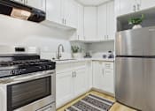 Thumbnail 11 of 37 - A modern kitchen with white cabinets and stainless steel appliances.