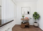 Thumbnail 24 of 37 - A small table with a plant on it sits in a corner of a room.