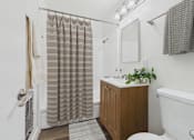 Thumbnail 11 of 55 - A bathroom with a white tub, a wooden cabinet, and a shower curtain.