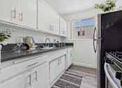 Thumbnail 2 of 55 - A kitchen with white cabinets and a black refrigerator.
