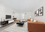 Thumbnail 6 of 37 - A living room with a brown couch, a coffee table, and a television.