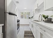Thumbnail 2 of 37 - A modern kitchen with white cabinets and a stainless steel refrigerator.