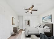 Thumbnail 1 of 12 - A bedroom with a bed, chair, and a ceiling fan.