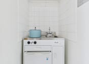Thumbnail 5 of 12 - A white kitchen with a blue pot on the stove.