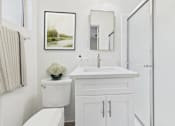 Thumbnail 7 of 12 - A white bathroom with a toilet, sink, and a framed picture on the wall.