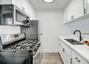 Thumbnail 6 of 83 - a kitchen with white cabinets and stainless steel appliances and a sink