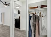 Thumbnail 14 of 83 - a walk in closet with a mirrored wall with clothes hanging on it