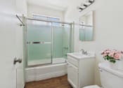 Thumbnail 15 of 61 - A white bathroom with a glass shower door and a white sink.