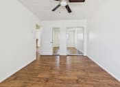 Thumbnail 11 of 61 - A room with a ceiling fan and wooden floors.