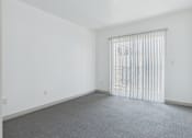 Thumbnail 7 of 35 - A room with a carpeted floor and a window with blinds.