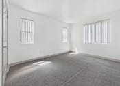 Thumbnail 8 of 35 - A spacious room with two windows and carpeted floor.