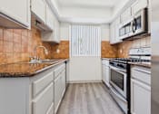 Thumbnail 2 of 35 - A kitchen with a brown counter top and white cabinets.