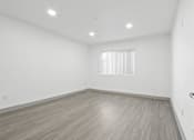 Thumbnail 7 of 24 - A room with a wooden floor and a window with blinds.
