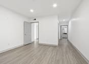 Thumbnail 9 of 24 - A long hallway with a white door at the end.