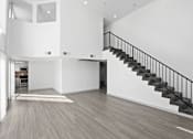 Thumbnail 5 of 24 - A spacious interior of a house with a staircase and a kitchen area.