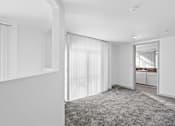 Thumbnail 15 of 24 - A white room with a grey carpet and a doorway leading to another room.