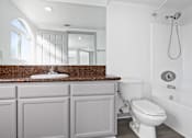 Thumbnail 16 of 24 - A white toilet sits next to a shower in a bathroom.