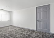 Thumbnail 17 of 24 - A room with a grey door and carpeted floor.