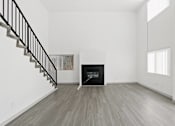 Thumbnail 3 of 24 - A modern living room with a fireplace and a staircase.