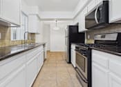 Thumbnail 2 of 15 - A kitchen with black appliances and white cabinets.