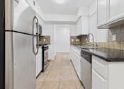 Thumbnail 1 of 15 - A kitchen with white cabinets and a black fridge.