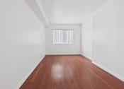 Thumbnail 8 of 15 - A room with wooden floors and white walls.