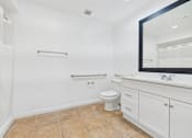 Thumbnail 13 of 15 - A white bathroom with a toilet, sink, and a mirror.