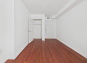 Thumbnail 9 of 15 - A long hallway with wood floors and white walls.