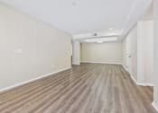 Thumbnail 22 of 30 - A long, empty hallway with wooden flooring and white walls.