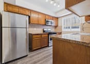 Thumbnail 17 of 30 - A kitchen with a stainless steel refrigerator and wooden cabinets.