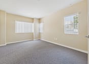 Thumbnail 26 of 30 - A room with a carpeted floor and two windows.