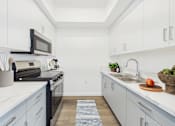 Thumbnail 1 of 13 - A kitchen with white cabinets and a black stove top oven.