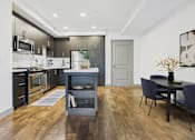 Thumbnail 17 of 40 - A modern kitchen with dark wood floors and a dining area with a table and chairs.