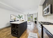 Thumbnail 16 of 40 - A kitchen with a white countertop and a black cabinet.
