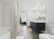 Thumbnail 12 of 40 - A bathroom with a white tub and a white toilet.