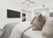 Thumbnail 5 of 40 - A bedroom with a bed, pillows, and a television on the wall.