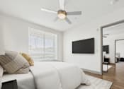 Thumbnail 6 of 40 - A bedroom with a bed, a ceiling fan, and a television.