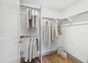 Thumbnail 9 of 40 - A white closet with clothes hanging on a rail.