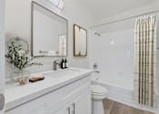 Thumbnail 10 of 73 - A white bathroom with a toilet, sink, mirror, and shower.