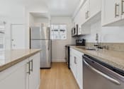 Thumbnail 100 of 228 - A kitchen with white cabinets and a granite countertop.
