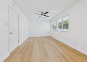 Thumbnail 117 of 228 - A room with a ceiling fan and wooden flooring.