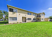 Thumbnail 15 of 38 - A beige building with a green lawn in front.