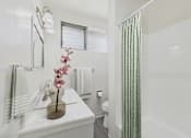Thumbnail 14 of 38 - A white bathroom with a green shower curtain.