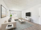 Thumbnail 2 of 38 - A living room with a white couch, a coffee table, and a flat screen TV mounted on the wall.