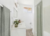 Thumbnail 7 of 38 - A bathroom with a white sink and a green plant on the counter.